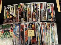 Photo displaying fifty high grade comic books laid out in two rows, bagged and boarded, featuring superheroes such as Robin, Green Lantern, Justice League, Batman, Superman, Wonder Woman, Flash, Aquaman, Deathstroke, Teen Titans, Azrael.