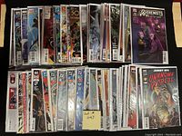 Photo showing two stacks of approximately 50 comic books, bagged and boarded, featuring covers for a variety of titles from Marvel and DC including X-Men and Unknown Worlds