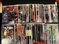 Photo shows 50 comic books laid out in two rows, all bagged and boarded. Various superhero themed comic books are visible.