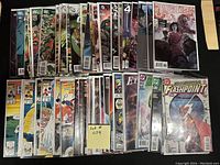 Full view of around 50 comic books spread side by side on a flat surface, showing bagged and boarded comics from various series and publishers.