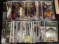 Photo showing 50 bagged and boarded high-grade comic books from Marvel and DC, including visible issues of Thunderbolts, Secret Six, Fear Itself, and others arranged in two rows.