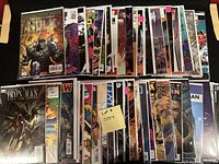 Photo shows a large collection of 50 comic books from Marvel and DC, bagged and boarded, with visible titles including Hulk and Iron Man at the front.