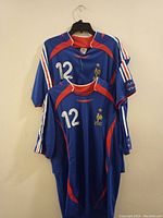 Two blue France soccer jerseys hanging on a wall, showing front with number 12 and FFF logo.