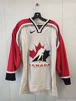 Front view of the hockey jersey showing the Canada logo and red sleeves.