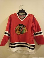 Front view of the red Chicago Blackhawks youth hockey jersey showing logo, stripes, and Reebok branding.