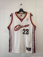Front view of white LeBron James Cleveland Cavaliers basketball jersey with number 23, Adidas and NBA logos visible.