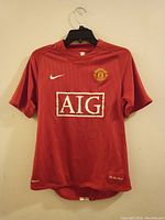 Front view of the red Manchester United soccer jersey with club crest, Nike logo, and AIG sponsor.