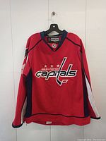 Front view of red Washington Capitals hockey jersey with logo on chest area.