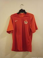 Front view of the red and orange Nike Canada soccer jersey showing logos and design details.