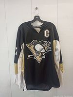 Front of the Pittsburgh Penguins jersey showing the team's penguin logo with Sidney Crosby's captain's C patch.