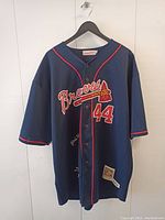 Front view of a signed Atlanta Braves baseball jersey with number 44 and red trim on blue fabric.