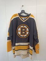 Front view of black, yellow, and white Boston Bruins hockey jersey with large Bruins logo on chest. The jersey is size XL with CCM tag visible.