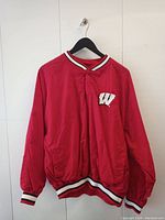 Front view of red Wisconsin Starter jacket with W logo on left chest and striped collar, cuffs, and hem.
