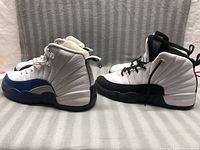 Side view of two pairs of Jordan shoes, blue/white size 4.5 and black/white size 3 pair.