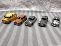 Front view of five vintage Dinky Toys die-cast cars arranged in a row showing varying paint condition.