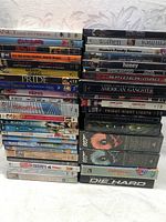 Stack of assorted DVD movies showing titles like 'Pride', 'Spider-Man', 'Die Hard', 'Alien', '007' and more.