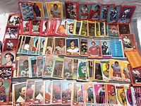 Photo capturing the assortment of vintage hockey and football cards laid out on a flat surface showing various players in uniform, including multiple rows of cards from the 1960s and 70s.