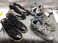 Four pairs of used Jordan running shoes in various colors and styles displayed on a grey surface.