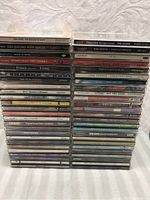 Photo showing a large stack of 50 Hip Hop, Soul and R&B music CDs in clear jewel cases, titles visible along the spines including soundtracks and artists like Prince and Tina Turner.