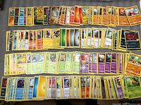 Top view showing multiple rows of Pokémon cards, featuring many different Pokémon types and colors, arranged in fan style.