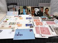 Overview of multiple Royal first day covers and envelopes with stamps and commemorative postmarks spread out on a surface.