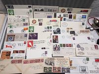Photo showing a spread of about 26 vintage first day stamp envelopes with various designs, stamps, and postmarks.