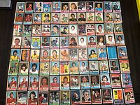 Top view showing a collection of 77 vintage hockey cards laid out in rows on a dark surface.