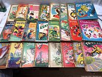 Top-down view of approximately 20 vintage Little Golden Books children's books laid out on table with colorful illustrated covers showing titles and wear.