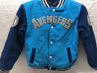 Front view of Marvel Avengers kids jacket size 7/8 with blue body, navy sleeves, snap buttons, and Avengers text patch.
