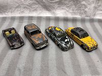 Overview photo of four vintage die-cast cars arranged in a row, showing paint wear