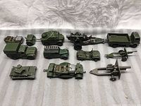 Overview of 9 vintage green Dinky Toys military toy vehicles and artillery, showing various types and sizes.