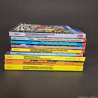 Spine view of all 8 Captain Underpants books stacked flat, showing titles and publishers.