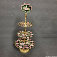 Front view of the 3-tier cloisonne earring stand, showing floral pattern on plates, gold-tone metal spacers and base, and decorative floral finial.