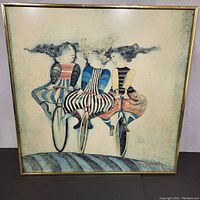 Front view of the framed painting depicting three cyclists in colorful clothing on bicycles.