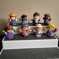 Front view of 8 Fisher Price Little People figures arranged in two rows showing variety of characters and colors.