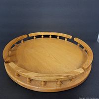 Top angle of circular wooden lazy Susan with spindle railing around the edge, showing natural wood grain.