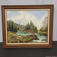 Frontal view of vintage framed landscape painting on canvas showing trees, river, and mountains.