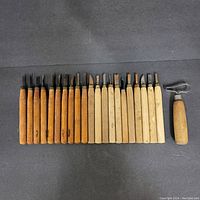 Two rows of wood carving tools including wooden handles with different blade shapes aged with some rust and wear.
