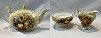 Front view of teapot, creamer and sugar bowl on neutral background
