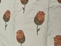 Close-up of floral pattern on cream background showing red, orange, yellow, and green flower details.