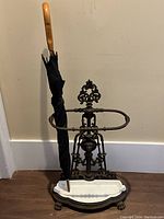 Umbrella stand with umbrella inserted, front view showing overall appearance, porcelain tray and claw feet.
