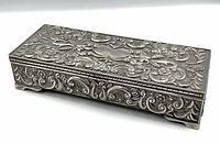 Full view of silver-plated rectangular jewelry box showing ornate embossed Art Nouveau floral and scroll patterns on the lid and sides.