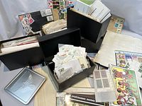 Overview of multiple black stock boxes, a tin and loose sheets with assorted stamps