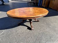 Overall view of round burr walnut coffee table on pedestal base