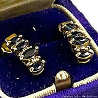 Close-up of bar-style earrings in blue velvet box showing sapphire and diamond details