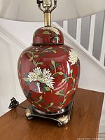 Front view of red enamel ceramic ginger jar base with white floral design on square brass foot.