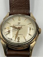 Close-up of watch dial, gold-plated case and strap end