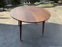 Full front view of round teak table outdoors on pavement