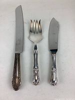 Three sterling serving pieces laid flat on white background showing handle detail and blade condition.