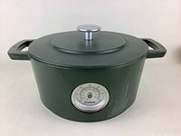 Front side view showing green enameled cast iron Dutch oven with temperature dial and handles.